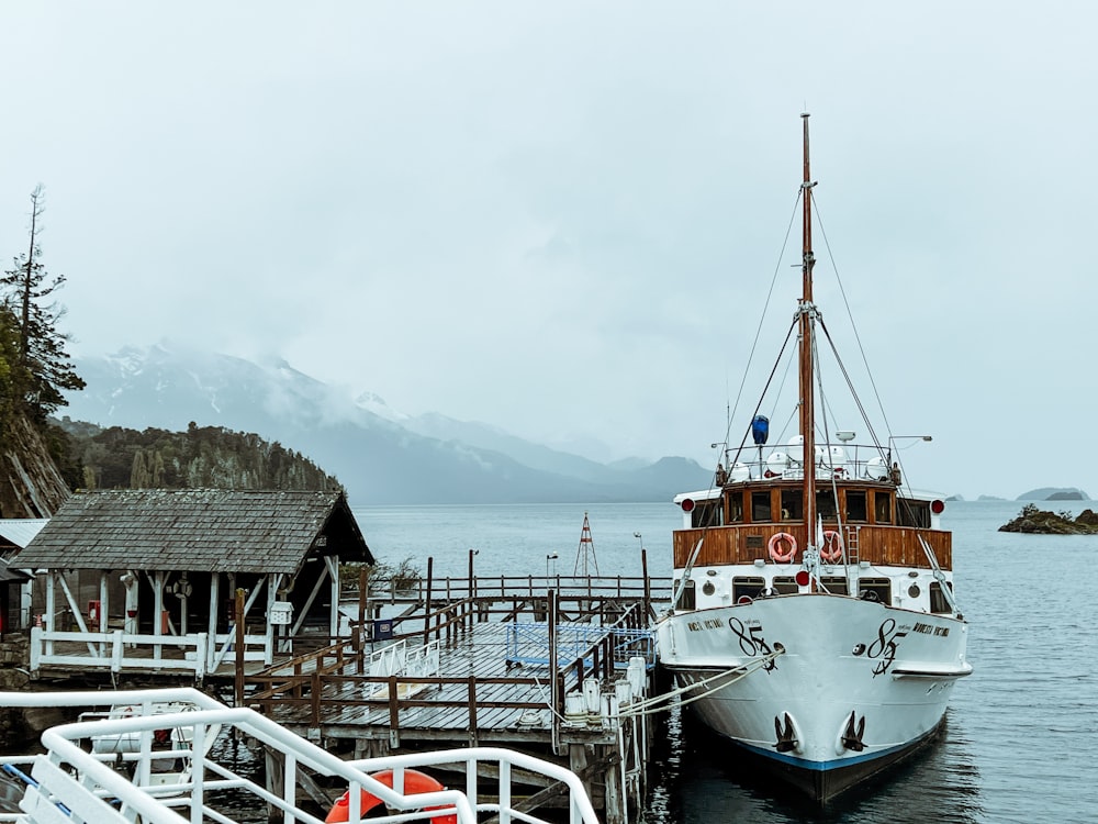 a boat docked at a pier with mountains in the background