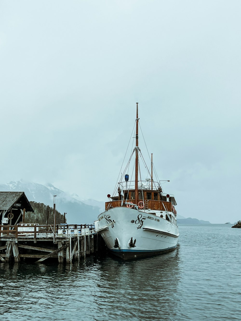 a boat docked at a pier with mountains in the background