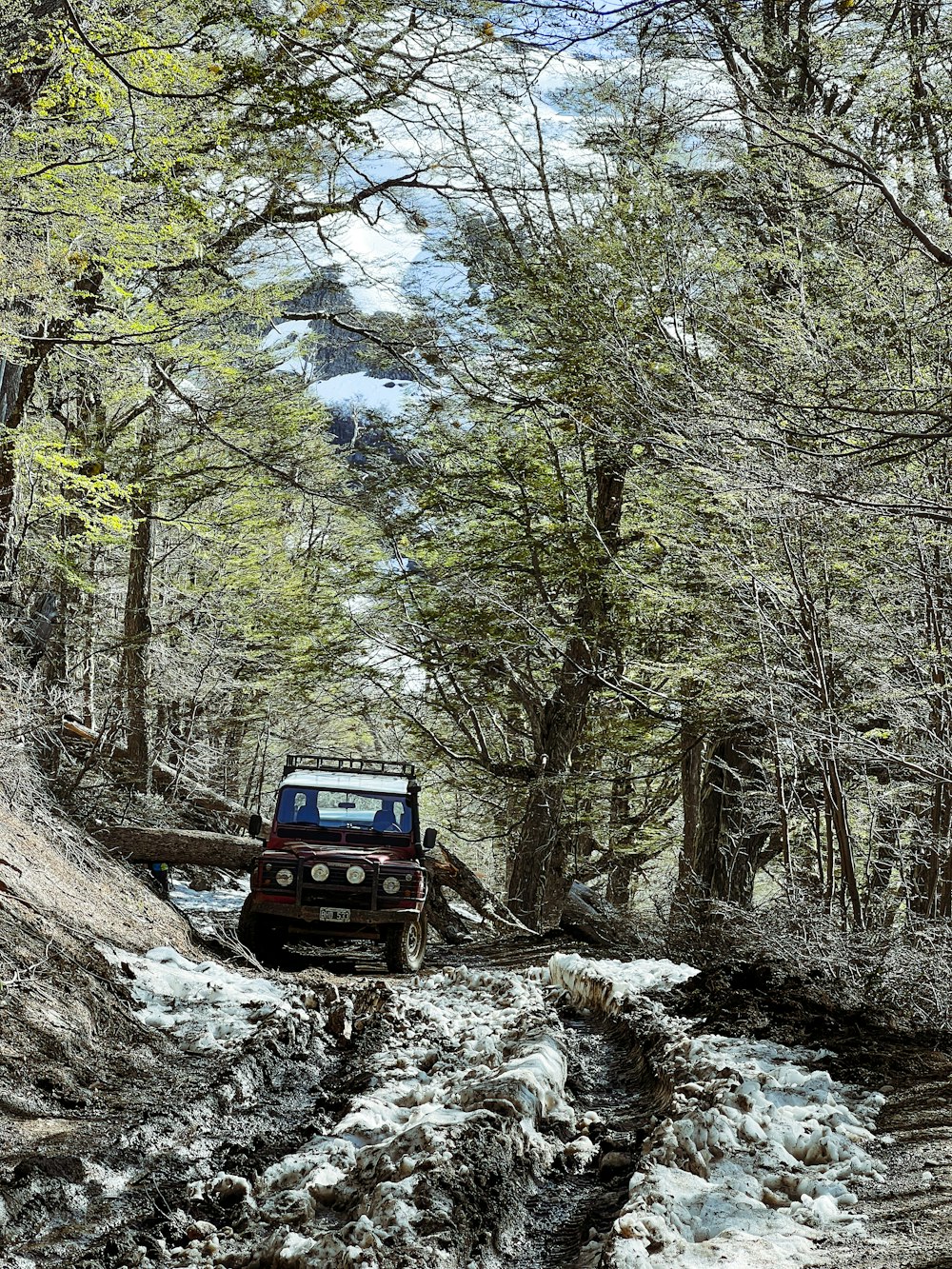a jeep driving down a muddy road in the woods