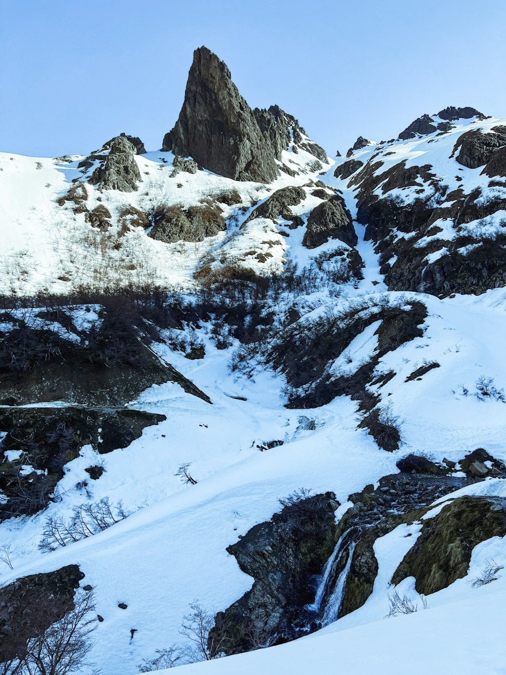 a snow covered mountain with a small waterfall