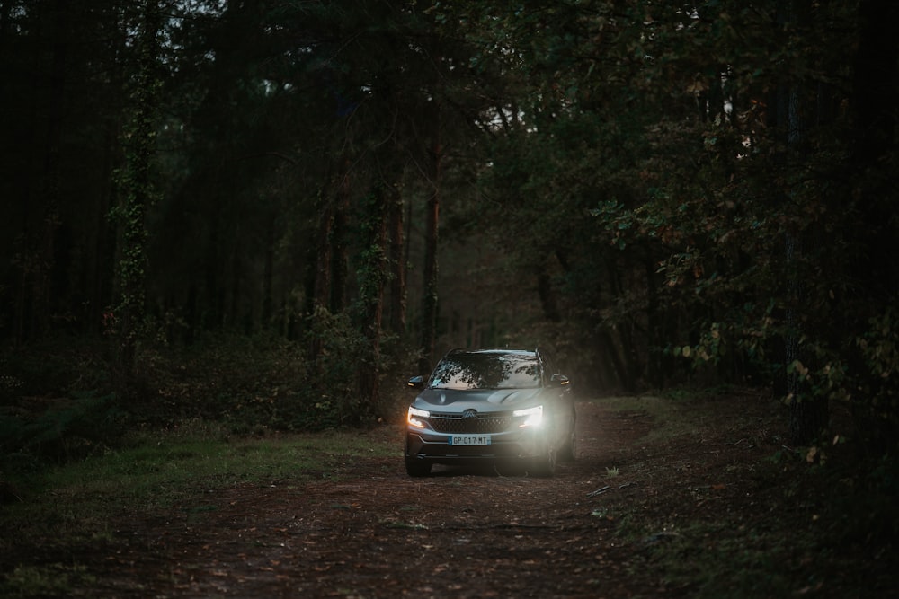 a car driving down a dirt road in the woods