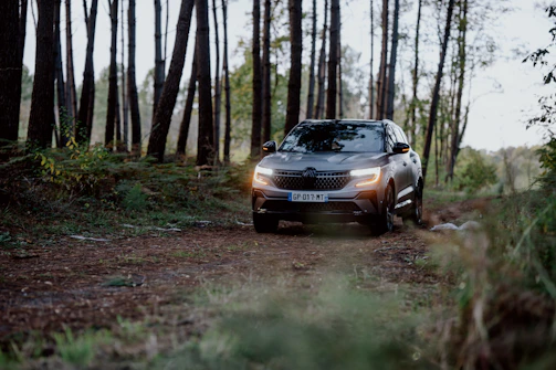 Side view of a Toyota SUV driving through a forest road