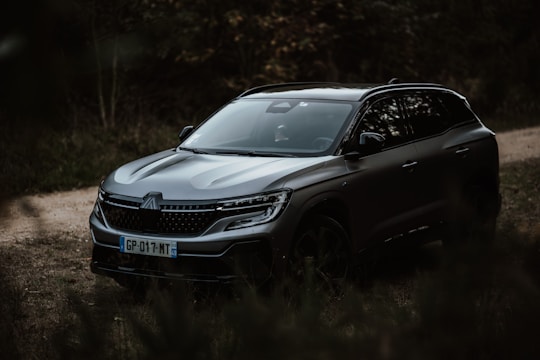 A modern 7-seater car parked against a backdrop of lush greenery.