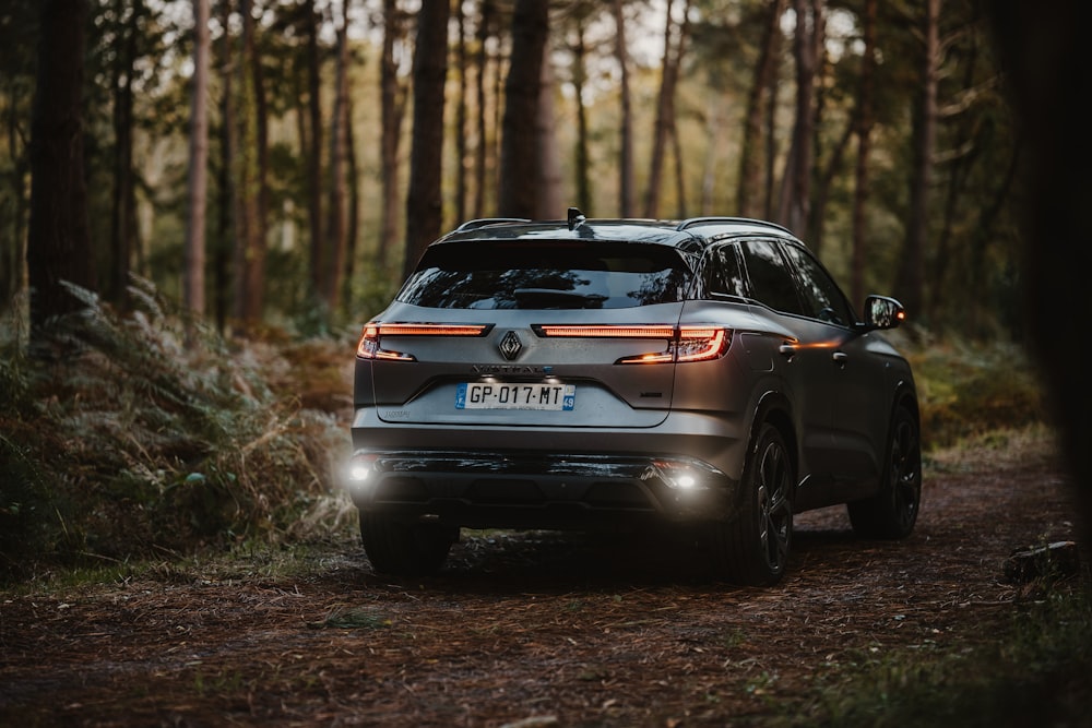 a car is driving through the woods on a trail