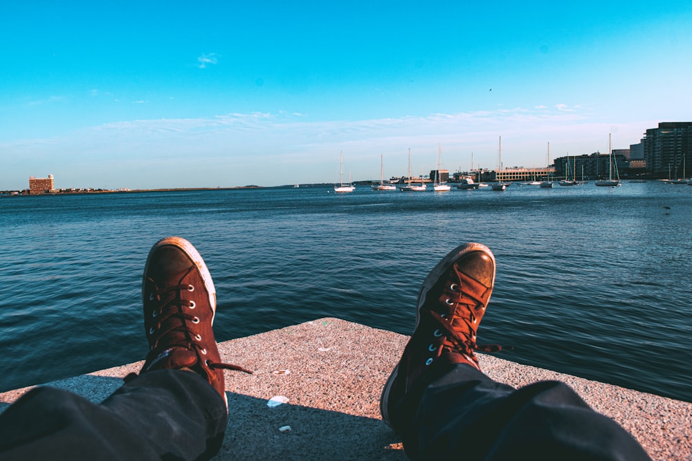 a person's feet are shown on a ledge overlooking a body of water