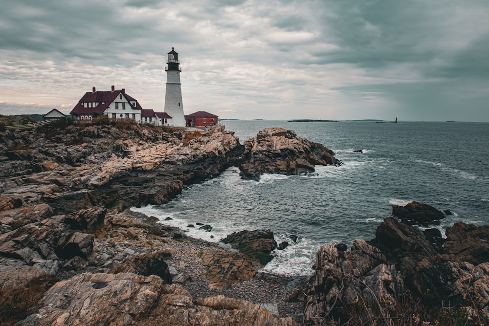 a light house sitting on top of a rocky cliff next to the ocean