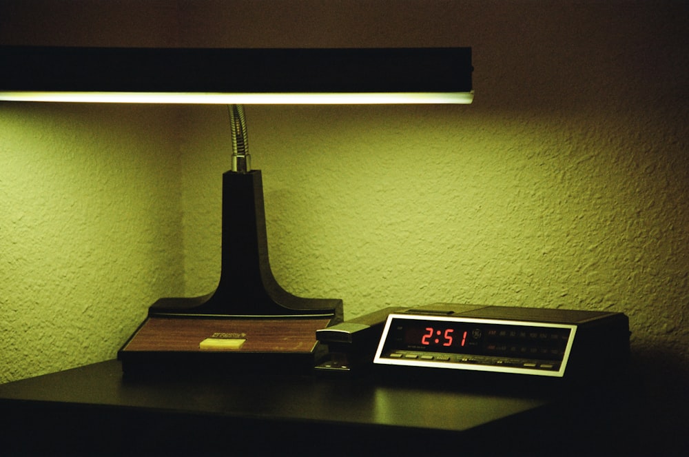 a clock sitting on a desk next to a lamp