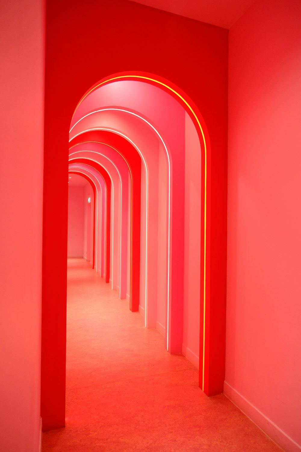 um longo corredor com paredes e arcos vermelhos