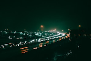 A nighttime shot of trucks moving along a highway under streetlights