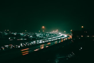 A nighttime shot of trucks moving along a highway under streetlights
