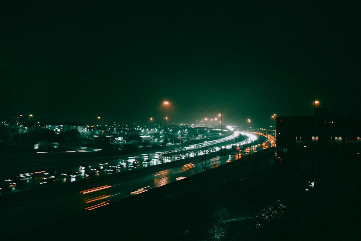 Autoroute plongée dans la brume de nuit, avec une longue file de phares de voitures
