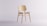 A modern, minimalist wooden chair designed by Carlo Vecchiola in a bright studio.