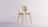 A minimalist wooden chair with a simple design, featuring a slightly curved backrest and seat. It has a light wood finish and is positioned against a plain, light background. The chair is made from smooth wooden materials with visible wood grain.