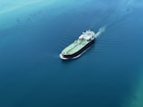 a green and white boat in the middle of the ocean