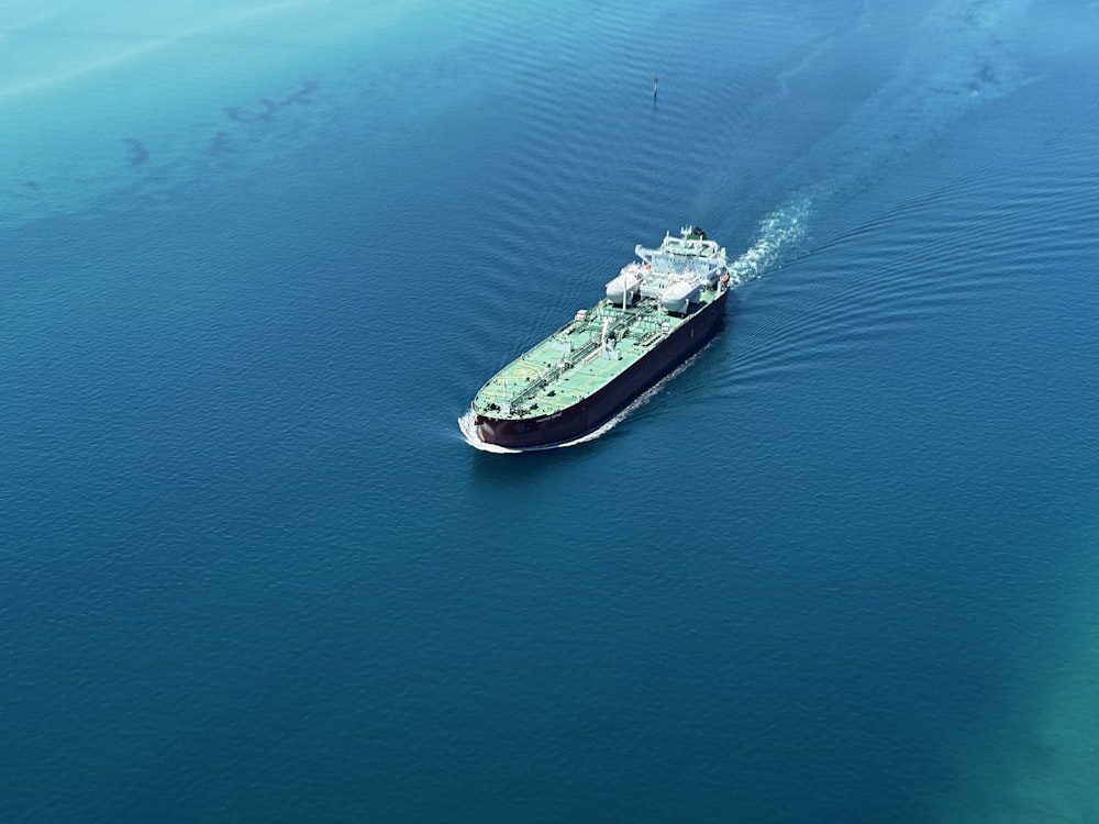 a green and white boat in the middle of the ocean