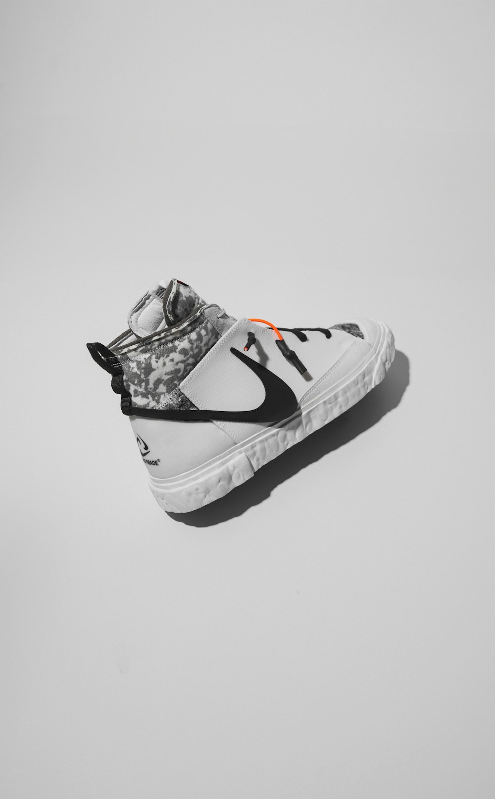 une paire de baskets blanches et noires sur une surface blanche