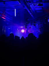 A mysterious dark room illuminated by neon blue and green lights casting shadows on abstract shapes.