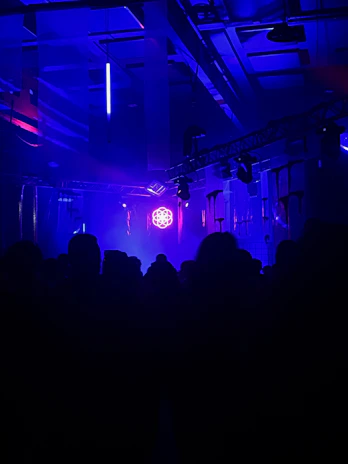 A mysterious dark room illuminated by neon blue and green lights casting shadows on abstract shapes.