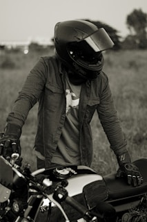 a person wearing a helmet and gloves standing next to a motorcycle