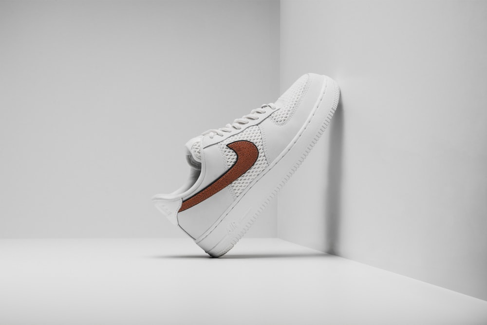 a white sneaker with a brown stripe on the side