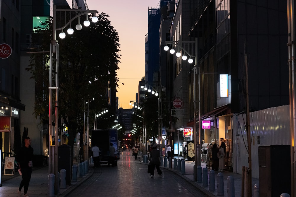 a city street at night with people walking on the sidewalk