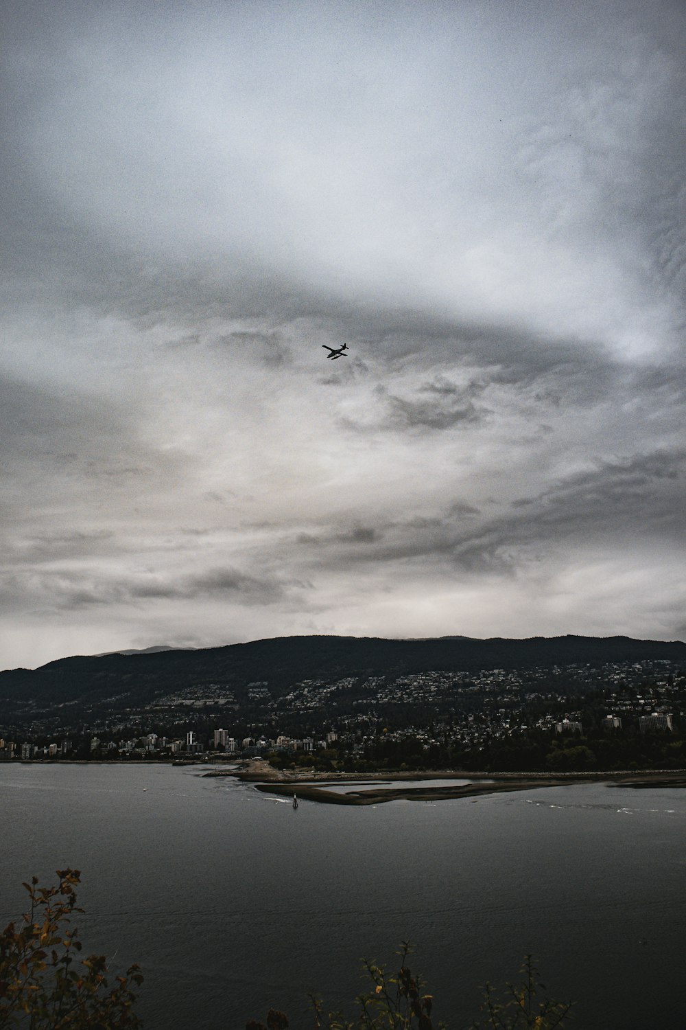 a plane flying over a body of water under a cloudy sky