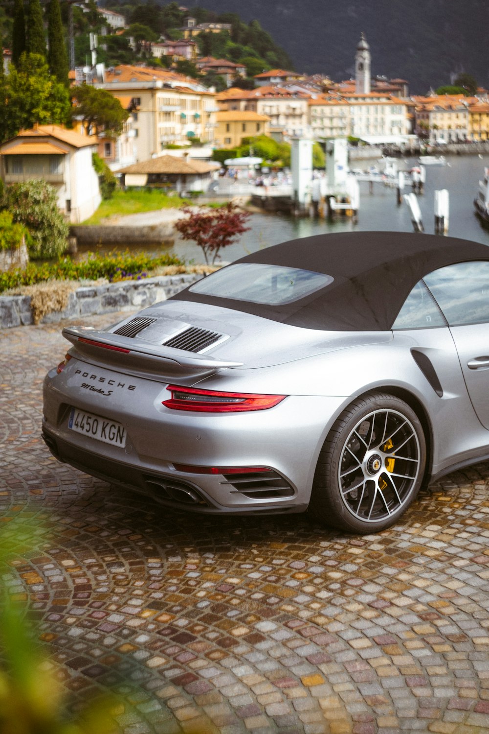 a silver sports car parked in front of a marina