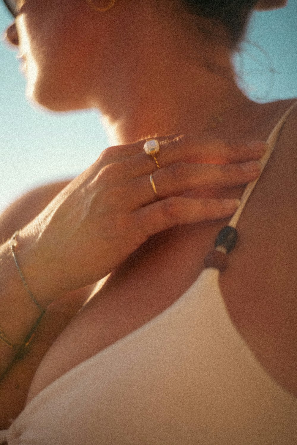 a woman wearing a white tank top and gold rings