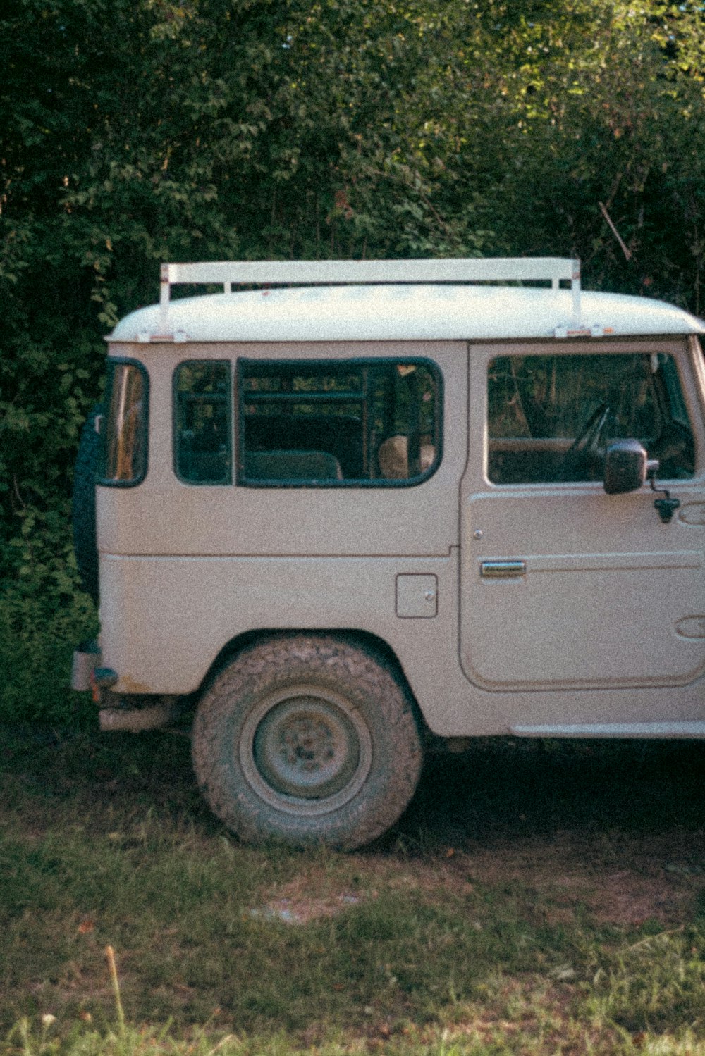 a white van parked in a field next to a forest