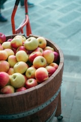 A rustic wooden barrel filled with freshly pressed apple cider in a sunlit orchard.