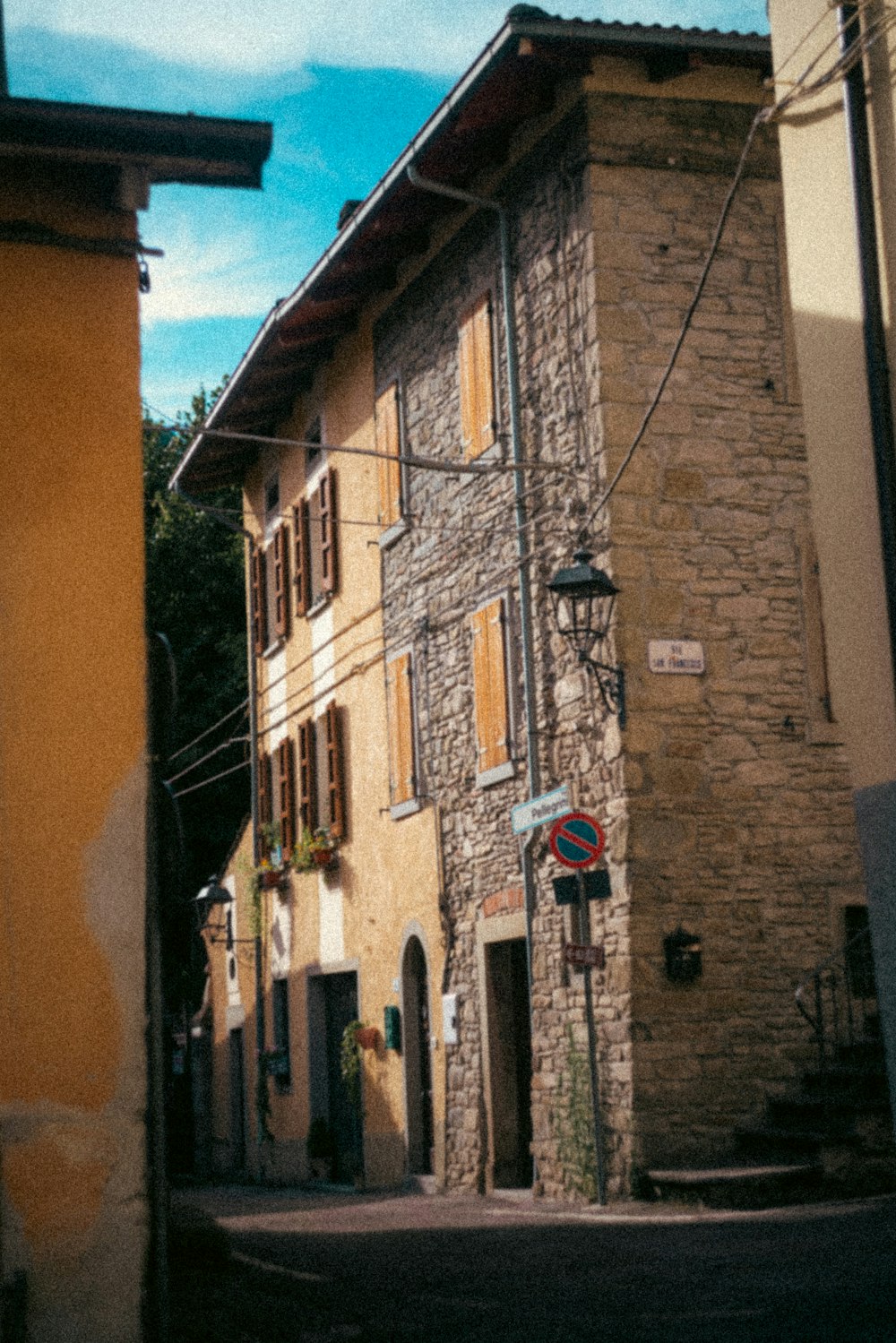 a narrow street with a stone building on the corner