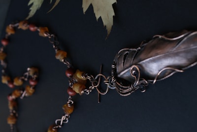 A necklace showcasing feathers and tiny wildflower charms against warm earth tones.