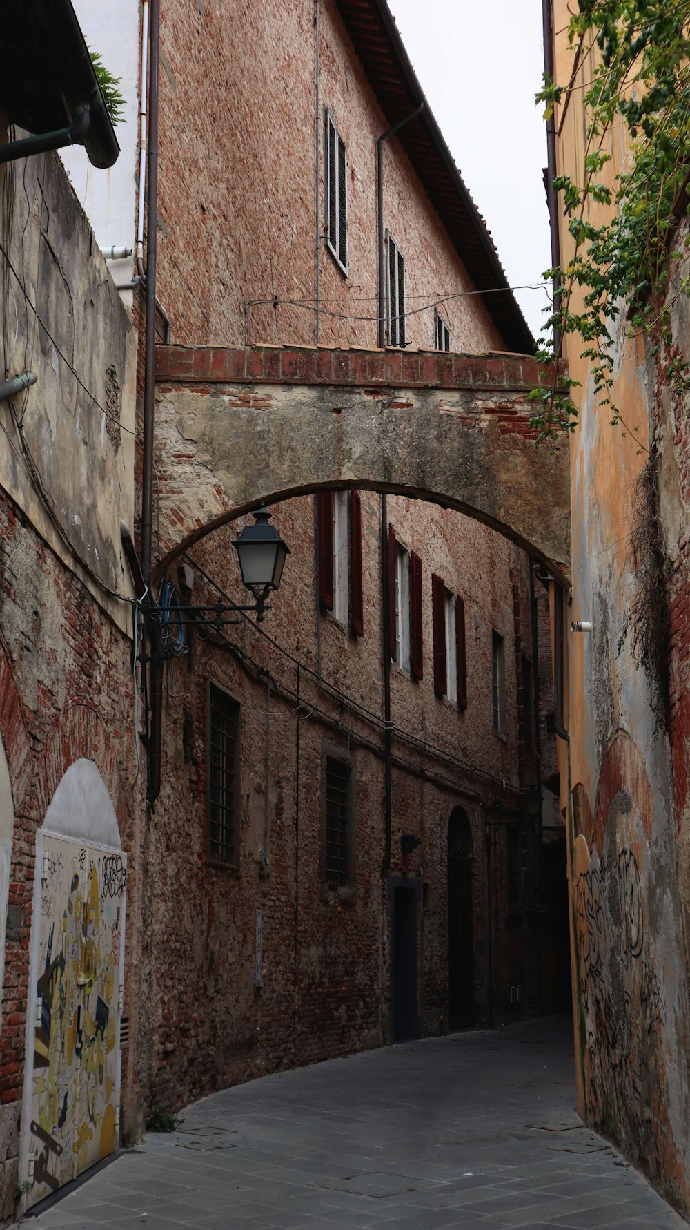 a narrow alleyway with a brick building and arched doorways