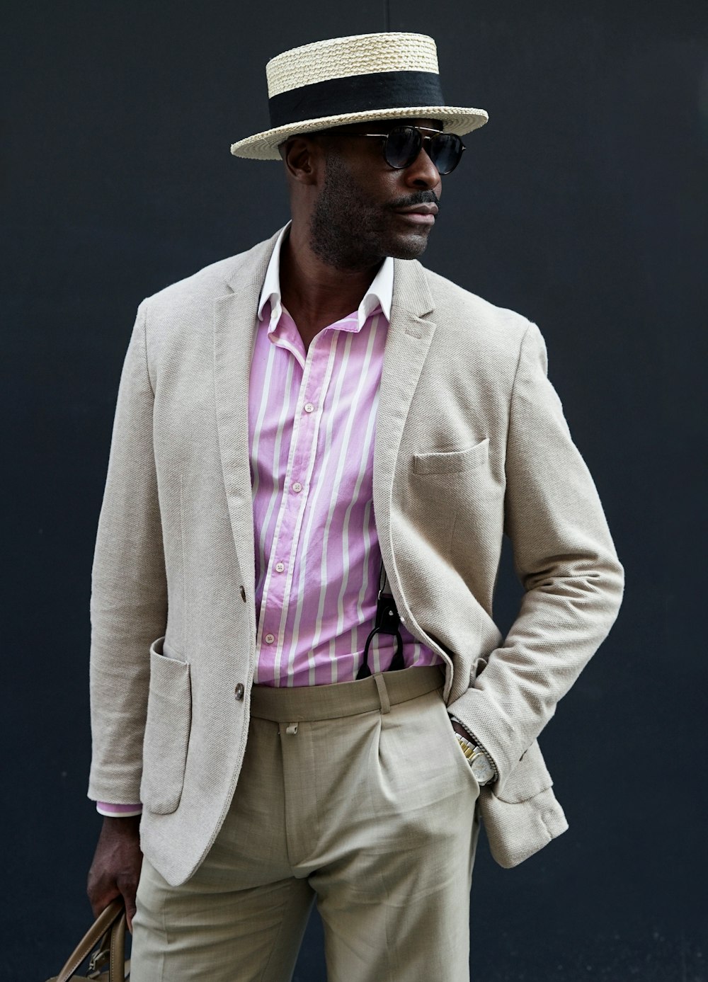 a man in a suit and hat is holding a bag