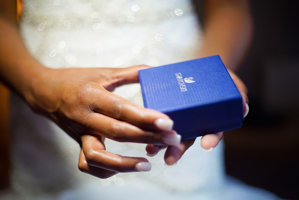 a close up of a person holding a blue box