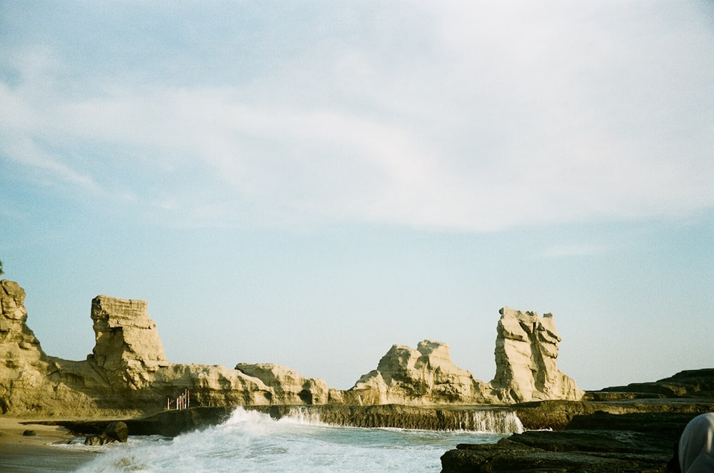 a person standing on a rocky beach next to the ocean