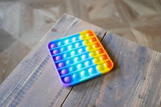 Close-up of a unique, fun gadget with bright colors and an unusual shape on a wooden table.
