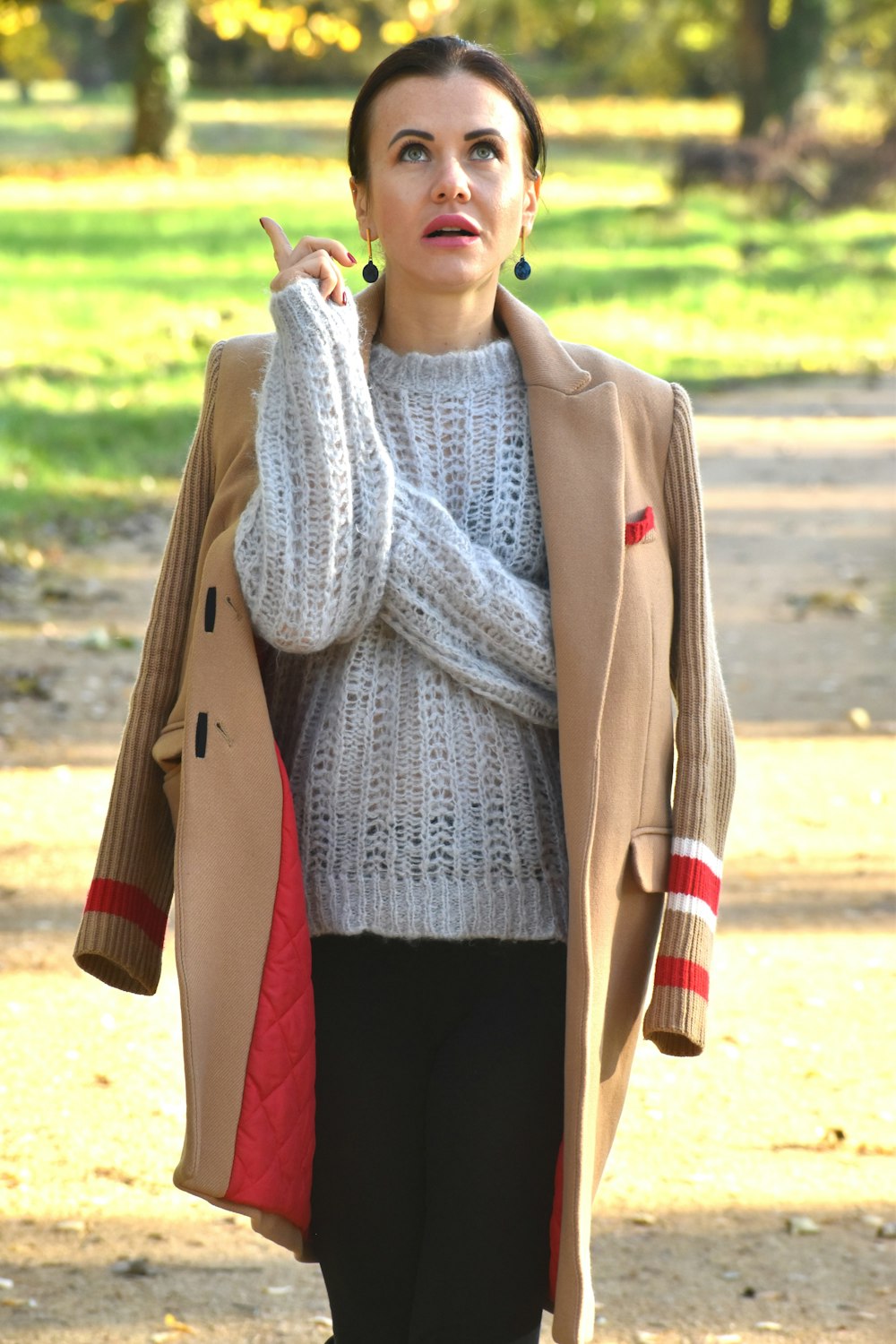 a woman in a coat and sweater is talking on a cell phone