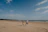 Couple walking hand-in-hand along a golden sandy beach under a bright blue sky