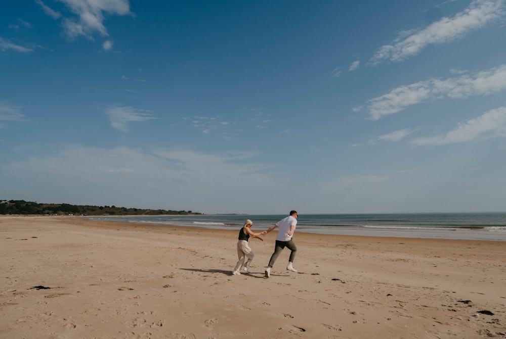 a man and a woman holding hands on a beach