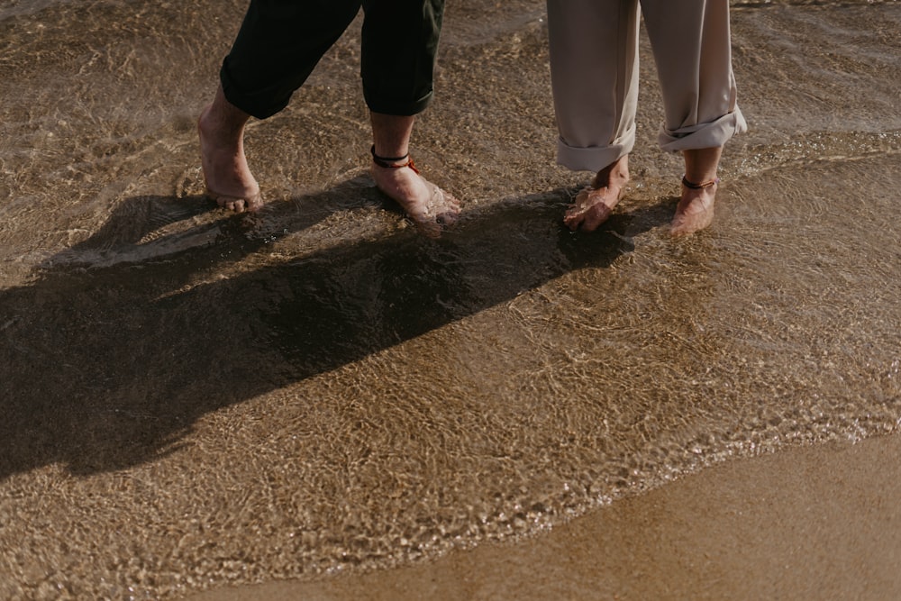 ein paar Leute, die auf einem Sandstrand stehen