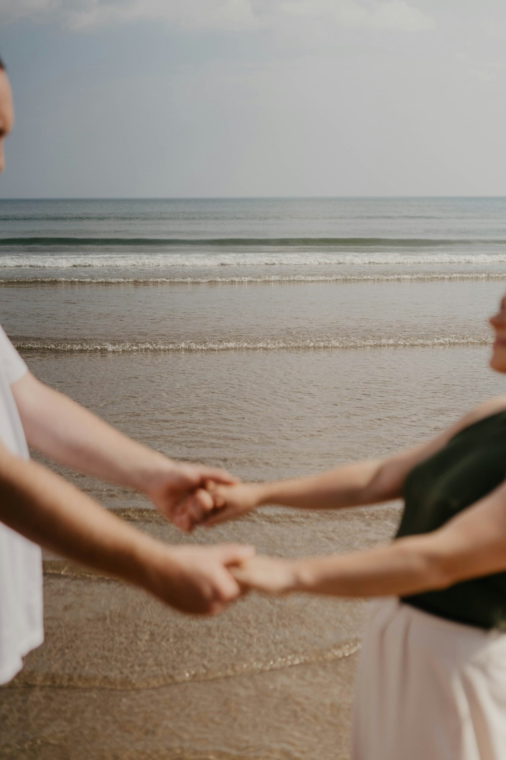 a man and a woman holding hands on the beach