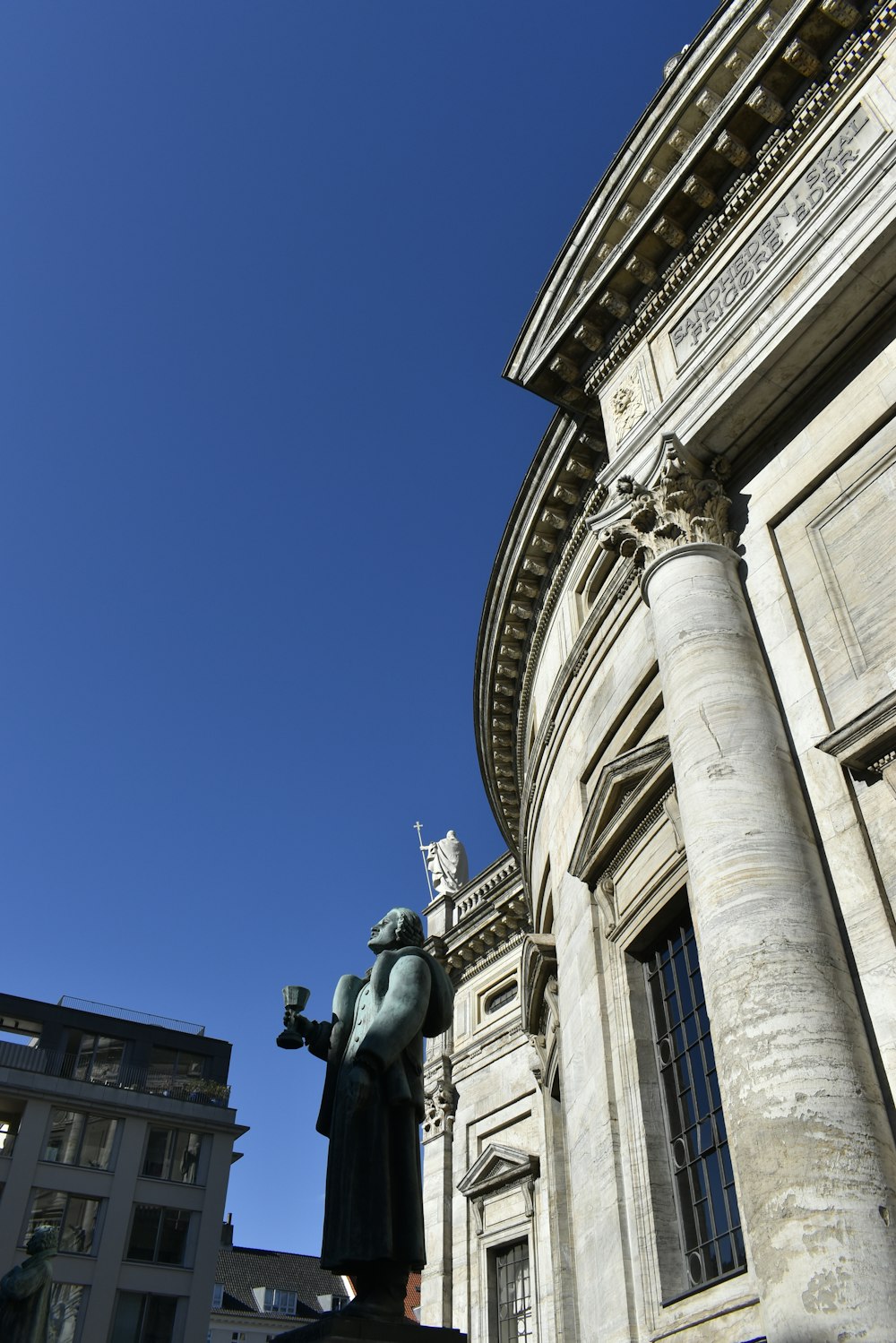 a statue of a man holding a candle in front of a building