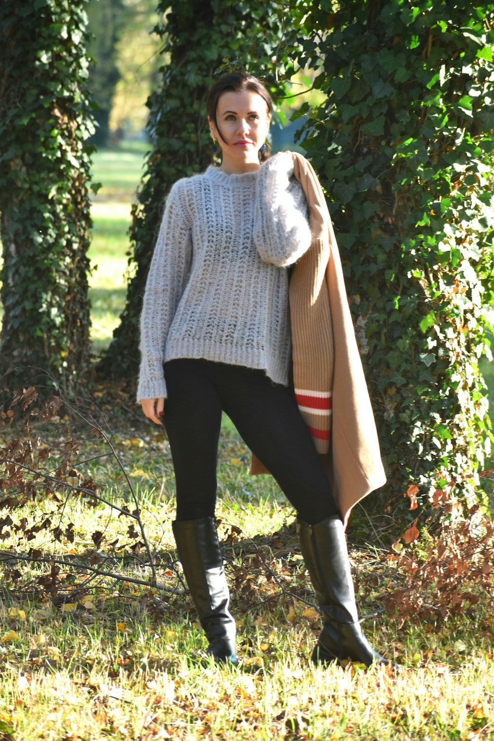 a woman standing in the grass with a coat over her shoulders