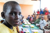 Smiling children receiving food and gifts in a welcoming setting.