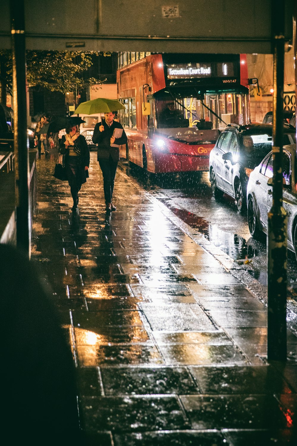 a group of people walking down a street in the rain