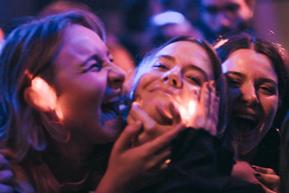 A close-up photo of the Trouble Department band members sharing a laugh backstage.