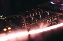 Close-up of a DJ mixing console with golden accents under soft lighting.