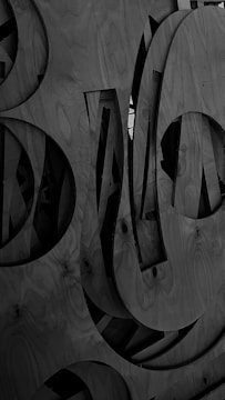Several large wooden panels with cutouts and silhouettes create a pattern of abstract shapes and curved lines. The texture of the wood grain is visible, enhancing the intricate design.