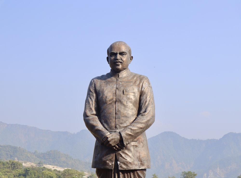 a statue of a man standing in front of a mountain